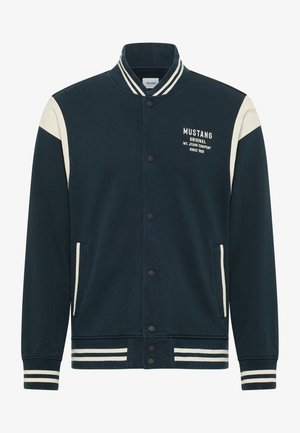 Dunkelblaues Bomberjacke mit crèmefarbenen Akzenten, Druckknöpfen, geripptem Kragen und Seitentaschen. Mit "MUSTANG"-Logo auf der Brust.