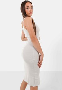 Ripp Midi-Kleid in Hellgrau mit einer taillierten Silhouette, dünnen Trägern und seitlichen Schlitzen für Bewegungsfreiheit. Weiche Textur und elastischer Stoff.