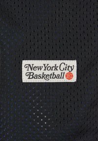 Svart mesh-stoff med små hull; merket "New York City Basketball" på et hvitt merke med en basketball-logo i oransje.