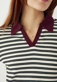 Cămașă polo cu dungi, cu guler vișinie, având dungi orizontale negre, bej și crem. Textură ribbată într-un design ajustat.