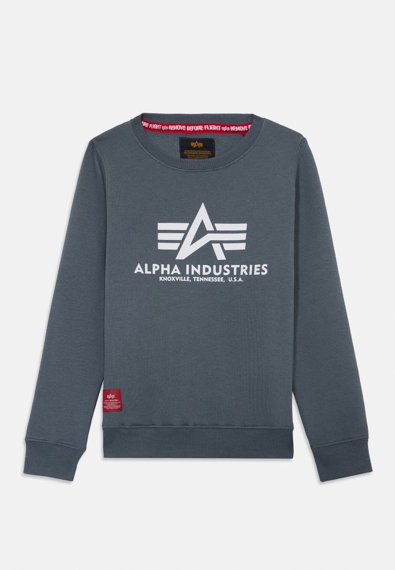 Sivi dukserica s okruglim izrezom, s istaknutim bijelim logotipom "ALPHA INDUSTRIES" i grafikom krila, rebrastim manžetama i crvenom oznakom.
