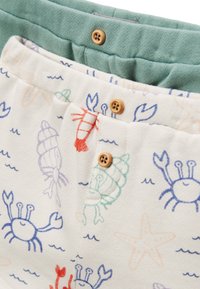 Shorts à motif de homards et de crabes en crème avec une ceinture verte. Comprend des boutons en bois et un tissu doux et texturé.