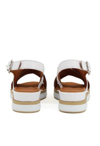 Sandali bianchi con fibbia, aperti sul retro e con plantare imbottito marrone. Presentano una suola stratificata bianca e beige. Materiale superiore liscia.