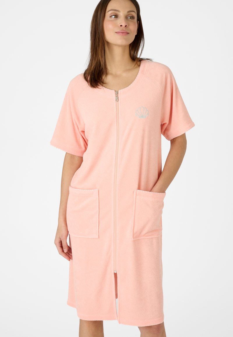 Accappatoio in spugna rosa con maniche corte, zip frontale, due tasche a toppa e un motivo ricamato a forma di conchiglia sul petto.