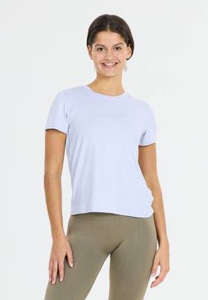 Lichtblauw T-shirt met korte mouwen gemaakt van een gladde stof, heeft een ronde halslijn en een ontspannen pasvorm, gecombineerd met strak zittende olijfgroene leggings.