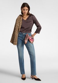 Donker mauve blouse met driekwartmouwen; lichtblauwe rechte jeans; bruine en beige luipaardprint sjaal; zijden sjaal om de taille geknoopt; donkere schoenen.