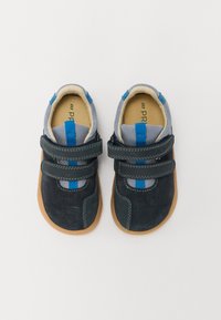 Zapatos de color azul oscuro y gris con acentos azules, materiales de ante y malla, dos correas de Velcro, suelas de goma y perforaciones para transpirabilidad.