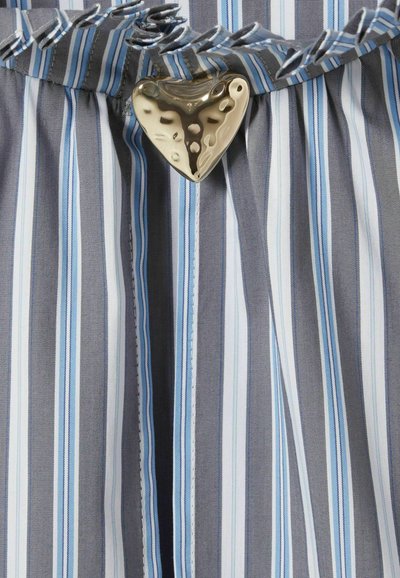 Tela a rayas en tonos de gris y azul con un acento metálico en forma de corazón y un volante en la cintura, presenta costuras blancas.