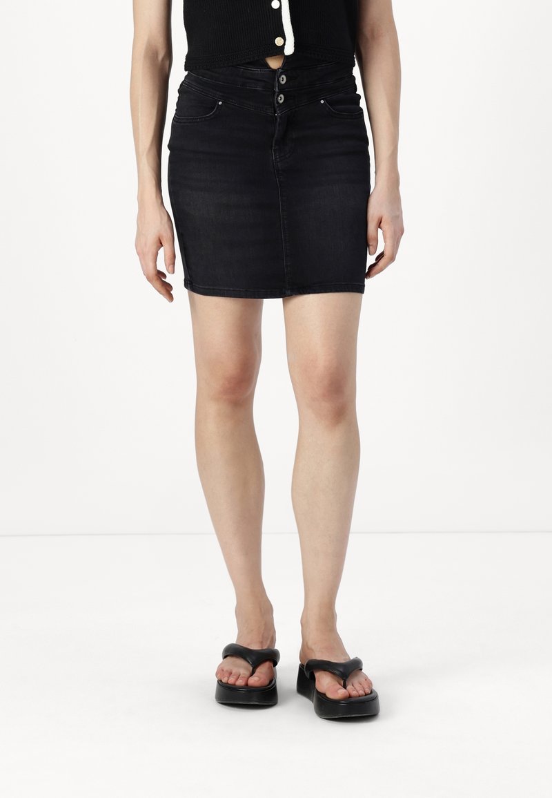 Černá džínová mini sukně s přiléhavým střihem, designem se pěti kapsami a zapínáním na knoflík. V kombinaci s černými platformovými sandály.