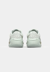 Scarpe da ginnastica verde chiaro con tomaia texturizzata, suole ammortizzate e accenti dorati discreti. Progettate per il comfort e le prestazioni.