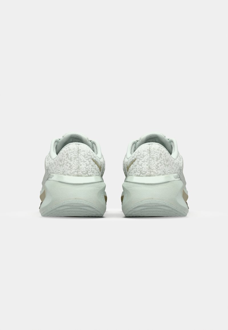 Zapatillas deportivas de color verde claro con parte superior texturizada, suelas acolchadas y sutiles detalles en dorado. Diseñadas para la comodidad y el rendimiento.