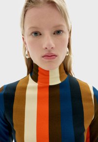 Turtleneck-top med markante, lodrette striber i orange, blå, brun og creme. Blødt stof med en tætsiddende pasform. Glat tekstur.