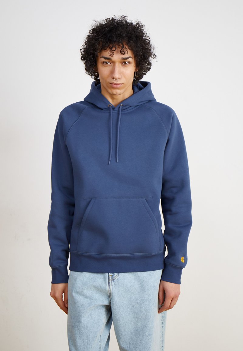 Navy blue hoodie with a front pouch pocket, drawstring hood, and ribbed hem. Features logo accent on the cuff and soft fabric texture.