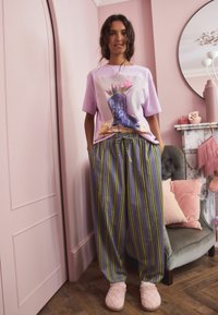 Lilac t-shirt with graphic of flowers in blue boots, paired with gray striped pants with yellow accents, and pink quilted slippers.