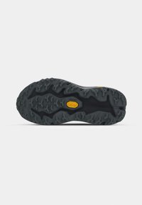 Black rubber outsole featuring a rugged, multi-directional tread pattern with a prominent yellow logo, designed for traction and durability.