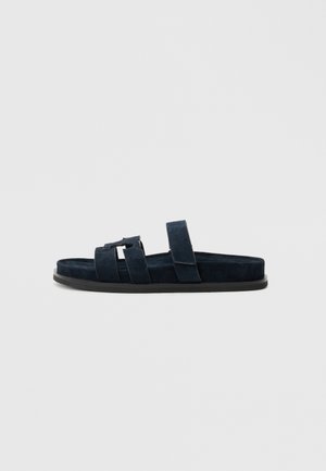 Navyblaue Slidesandale aus weichem Wildleder mit zwei breiten Riemen und einem strukturierten Fußbett, versehen mit einer strapazierfähigen, schwarzen Gummisohle.