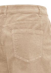 Pantalon en velours côtelé beige avec une poche arrière, des passants de ceinture et des coutures visibles sur un tissu texturé.