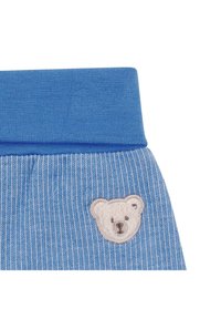 Tissu côtelé bleu avec une ceinture solide bleue et un visage de nounours blanc brodé près de l'ourlet.