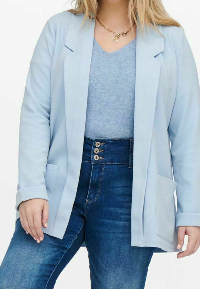 Light blue blazer with a smooth texture, two front pockets, and notched lapels, worn over a soft blue top and high-waisted denim jeans.