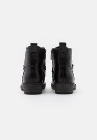 Schwarze Leder-Stiefeletten mit seitlichen Reißverschlüssen, einer leicht strukturierten Oberfläche und Blockabsätzen. Mit Zuglaschen für einfaches An- und Ausziehen.