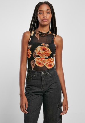 Svart ermeles topp med et blomstermønster av oransje roser, med et litt gjennomsiktig stoff og høy hals. Brukt med mørk denimbukse.