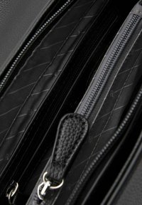 Borsa nera con zip e scomparti multipli, caratterizzata da un esterno testurizzato, una fodera liscia e hardware di tonalità argento. Interno con sottili linee diagonali.