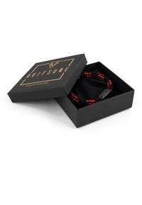 Scatola nera regalo con dettagli dorati, contenente un cordone intrecciato nero e rosso e una fodera in tessuto nero all'interno della scatola.