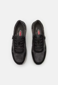 Black and grey lace-up shoes with suede and mesh materials, featuring a zip closure on one side and rubber sole for grip.