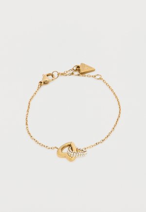Βραχιόλι αλυσίδας από χρυσό με καρδιά σε σχήμα συνδέσμου, διακοσμημένο με μικρές διαφανείς πέτρες, με κούμπωμα αστακού και ετικέτα μάρκας.