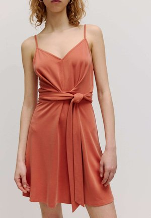 Ärmelloses, rostfarbenes Kleid mit V-Ausschnitt und geknotetem Taillen-Detail. Hergestellt aus weichem Stoff mit einem fließenden Rock und minimaler Naht.