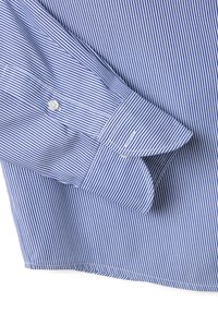 Camisa de dress a rayas azul y blanca con puños abotonados, textura suave y un dobladillo ligeramente curvado. Las rayas horizontales están espaciadas de manera uniforme.
