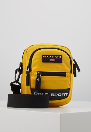 Gele Polo Sport crossbody tas met een zwarte verstelbare band, voorzakken met rits en Polo Sport logo patches.
