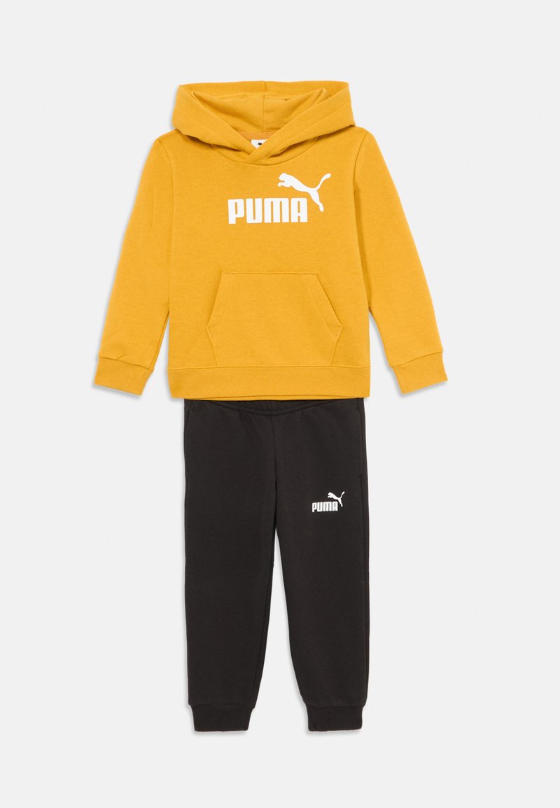 Žltá mikina Puma s klokaním vreckom, v kombinácii s čiernymi teplákmi Puma, obidve so bielym logom Puma.