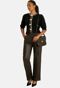 Melnas ribotas džemperis ar bežām lentītēm, kombinēts ar augsto jostu mākslīgās ādas biksēm. Aksesuāriem pievienota melna plecu soma.