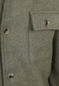 Groene wolmix jas met een textuurafwerking, grote knoopsluiting en een borstzak met klepdetail.