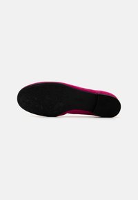 Zapato de ante fucsia tipo slip-on con suela de goma negra texturizada, que presenta un motivo floral. El diseño es de bajo perfil sin herrajes visibles.