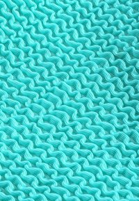 Texturerad tyg i en ljus turkos färg med ett vågigt mönster. Materialet verkar lätt och böjligt, vilket skapar djup i designen.