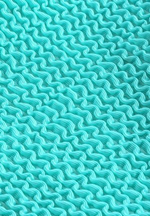 Tissu texturé d'une couleur turquoise vive avec un motif ondulé. Le matériau semble léger et pliable, créant de la profondeur dans le design.