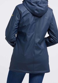 Námořnicky modrá nepromokavá bunda s kapucí, která má hladkou, lesklou texturu a středně dlouhý střih. Na rukávu je výrazné logo.