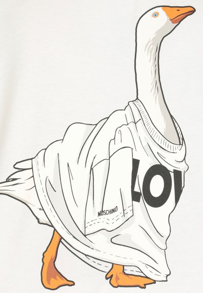 Oca che indossa una T-shirt bianca di Moschino con lettere nere parzialmente visibili, in piedi con piedi e becco arancioni.