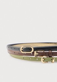 Τρεις λεπτές δερμάτινες ζώνες σε μαύρο, καφέ και ελαιδί, η κάθε μία με πόρπες χρυσού χρώματος, στοιβαγμένες οριζόντια σε ανοιχτό φόντο.