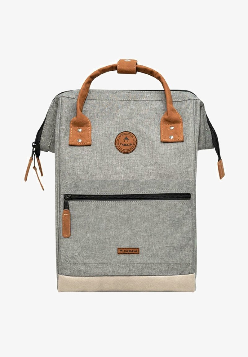 Grau canvas Rucksack mit braunen Lederakzenten, einem oberen Griff, einer frontalen Reißverschlusstasche und einem runden Logo-Patch. Der untere Abschnitt hat eine beigefarbene Einfassung.