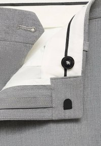 Grauer Stoff mit einem strukturierten Muster, mit einem weißen Innenfutter und einem schwarzen Knopfakzent. Beinhaltet eine Reißverschlusstasche für zusätzliche Details.
