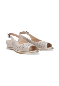 Beige Slingback-Wedgeschuhe mit offenem Zehenbereich, perforiertem Design und verstellbarem Schnallenverschluss. Sie verfügen über eine strukturierte Sohle mit einem kontrastierenden weißen Akzent.