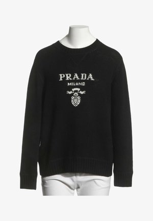 Jersey negro de manga larga con texto y logo blanco "PRADA MILANO" en el pecho, mostrado en un torso de maniquí blanco.
