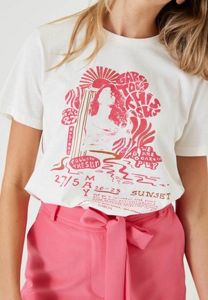 Witte T-shirt met een rode grafiek van een vrouw, zon en tekst ter promotie van een muziek evenement op 27 mei, gecombineerd met hooggeritste roze broek die om de taille knoopt.