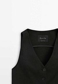 Zwarte vest met een V-hals, gemaakt van gestructureerde stof, met drie knopen en een label aan de binnenkant. Strak, minimalistisch ontwerp.