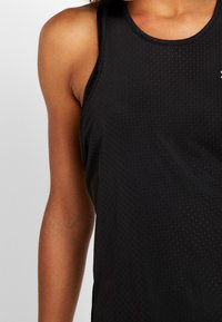 Camiseta deportiva negra sin mangas con tela texturizada, dise�ño sin mangas y un sutil detalle de logo en el pecho. Material liso y ligero.