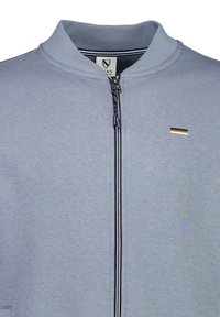 Jasnoniebieska kurtka zapinana na zamek z kołnierzem stójkowym, z małym złotym akcentem i granatowymi paskami wzdłuż zamka. Wykonana z miękkiej mieszanki bawełny.