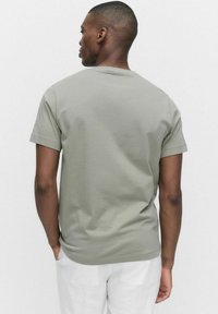 Kortärmad olivgrön t-shirt i mjuk bomull med rund halsringning; minimalistisk design utan synliga logotyper eller mönster.